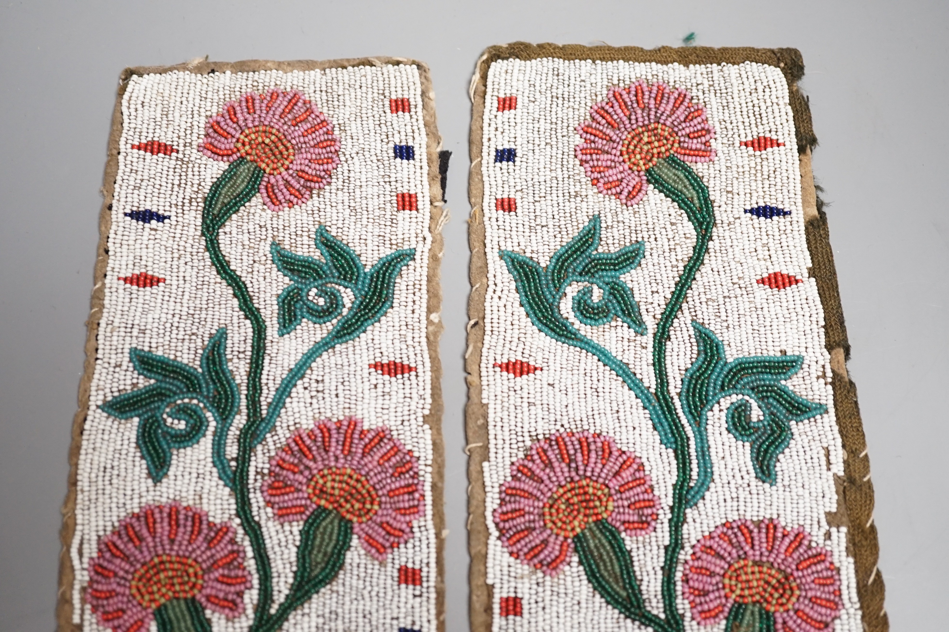 A fine pair of Native American Plains Indian rectangular beadwork panels, with floral designs and tribal markings, leather backing with remains of fabric edges, length 30cms